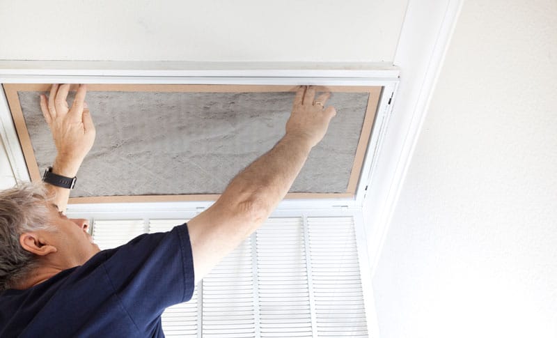 Man replacing air filter in HVAC system because of uneven air flow