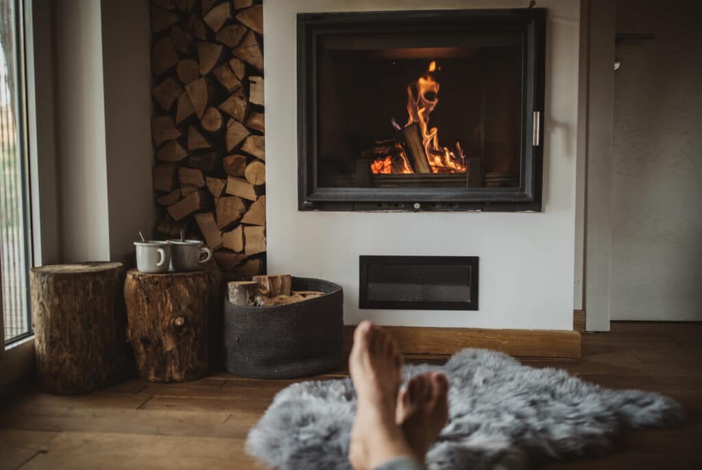 Person enjoying a night by the fire with a neat stack of firewood next to the fire.