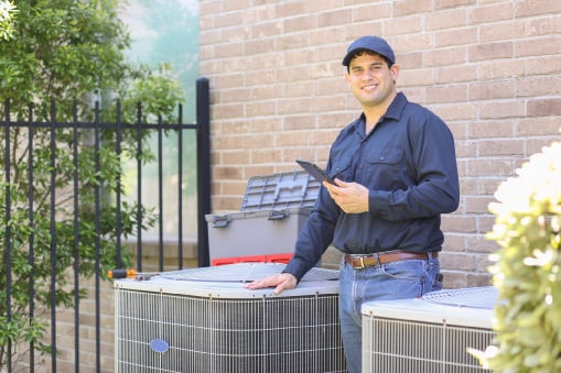 Zone employee posing in-front of a carrier HVAC outside and next to a carrier unit at a home